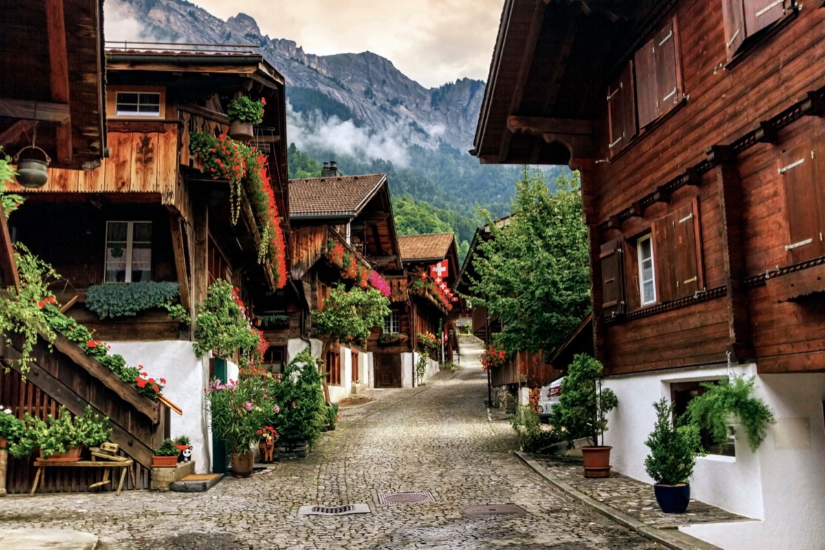 Rue pavée du village de Brienz, dans le canton de Berne, bordée de chalets en bois fleuris au pied des montagnes