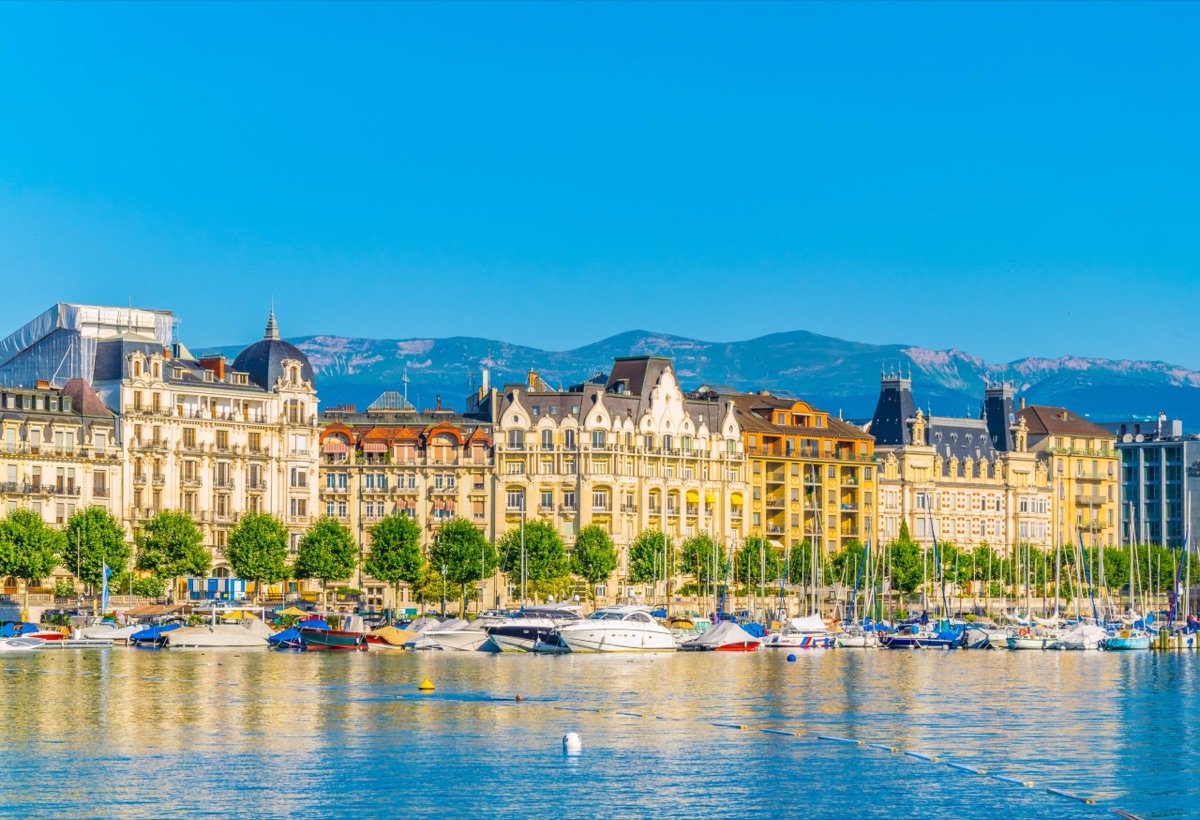 Immeubles anciens et bateaux amarrés sur la rive droite du Léman à Genève, montagnes en arrière-plan